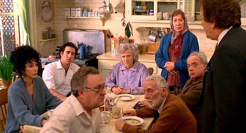The climatic scene in Moonstruck (1987) for Loretta Castorini comes with no privacy, little support, but hey, there’s coffee on the stove if anybody wants some. Clockwise from Loretta (Cher), Ronny Cammareri (Nicolas Cage), Rose Castorini (Olympia Dukakis), Rita Cappomagi (Julie Bovasso), Raymond Cappomagi (Louis Guss), Johnny Cammareri (Danny Aiello), Grandpa “Pop” Castorini (Feodor Chaliapin, Jr.), Cosmo Castorini (Vincent Gardenia).