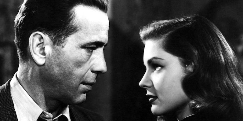 Here, Private Det., Phillip Marlowe (Humphrey Bogart) and his rich client’s pretty, eldest daughter, Vivian Rutledge (Lauren Bacall) size each other up and exchange double entendres in The Big Sleep (1946).